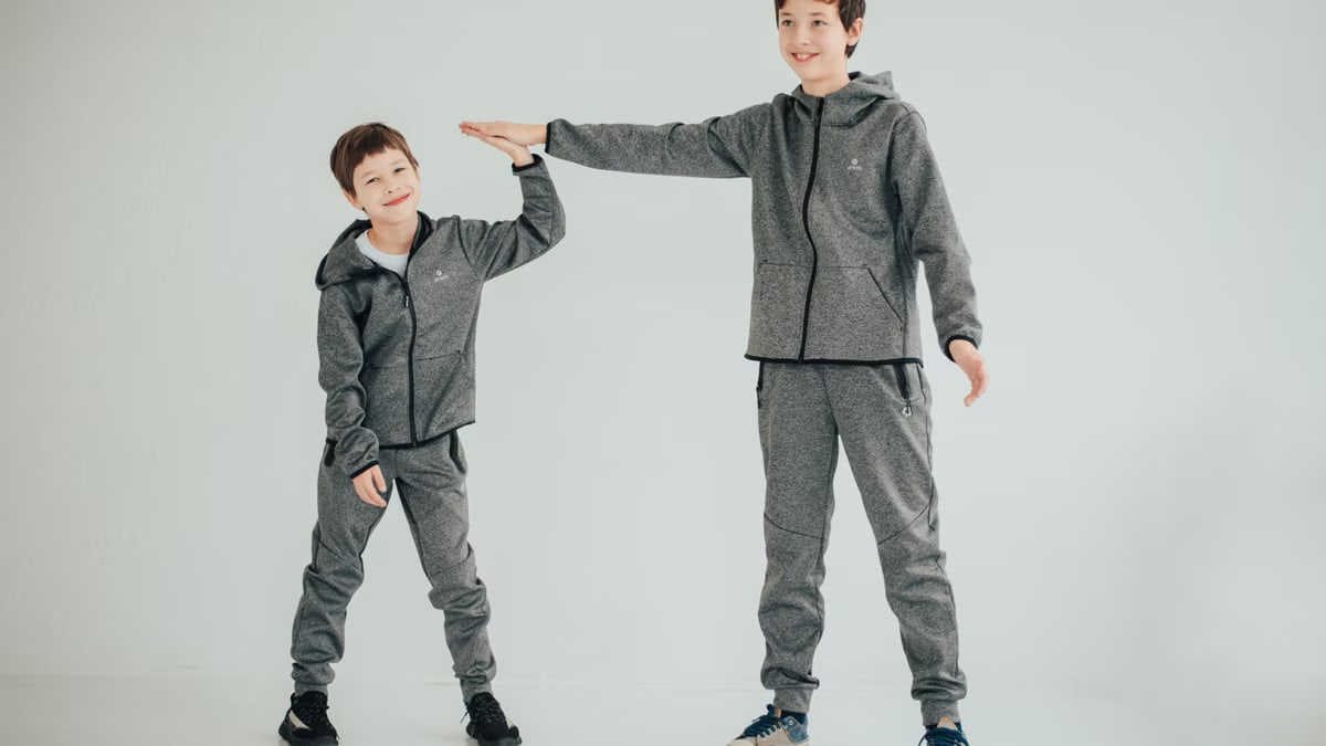 Two brothers sharing a high-five in matching gray outfits on a white background. Studio captured.
