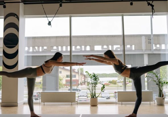 Two women performing yoga poses in a contemporary indoor studio.